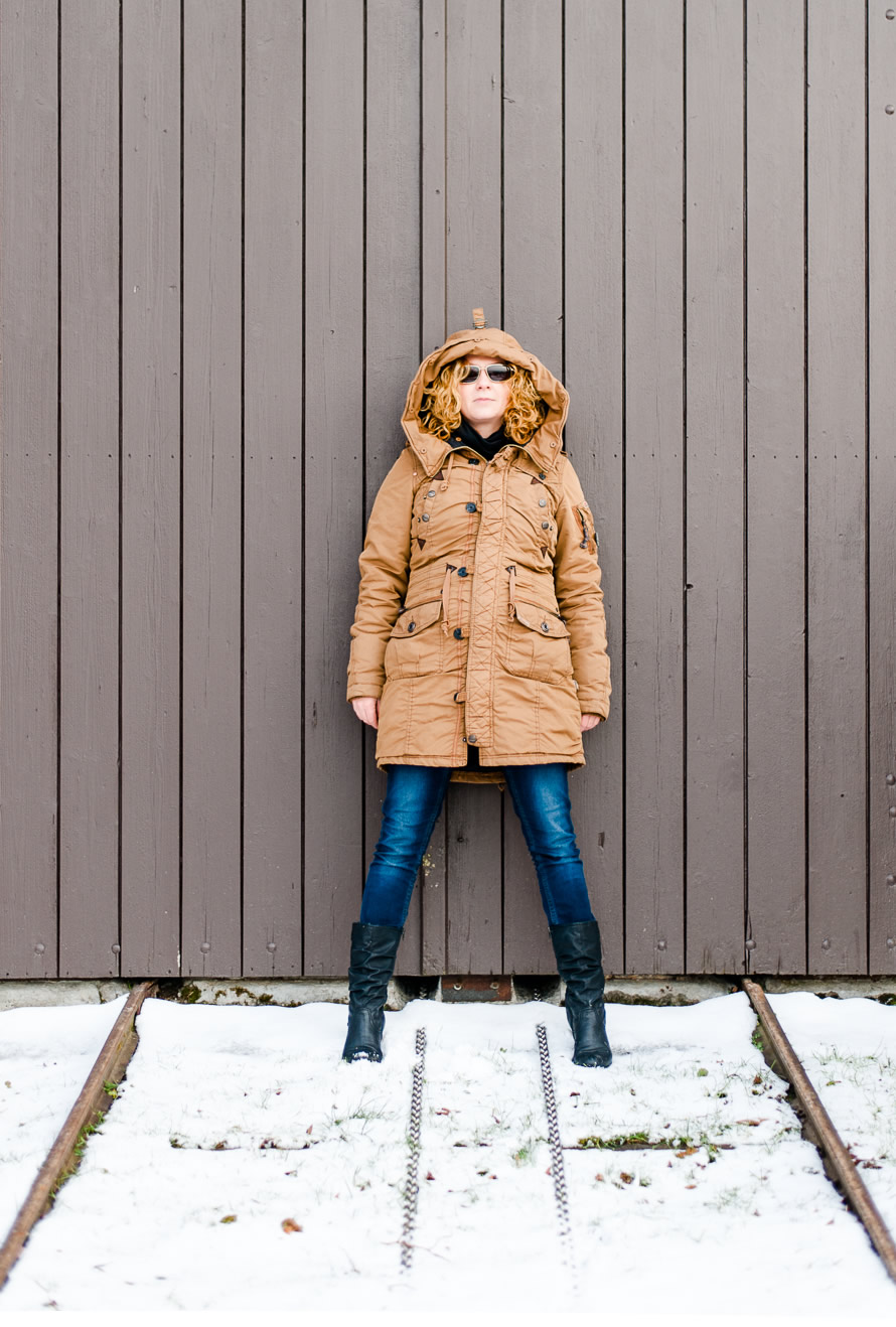 Portrait Frau an einer Holzwand im Wintermantel