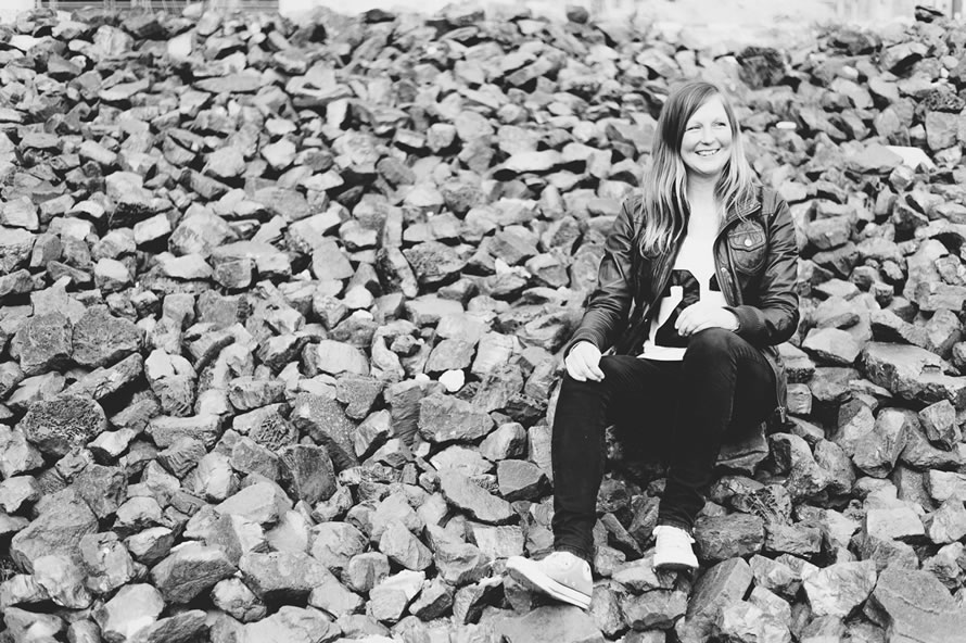 Katja sitzt auf schwarzen Steinen